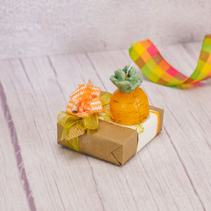 a sampler box of assorted chocolates is wrapped and topped with a petite carrot candle