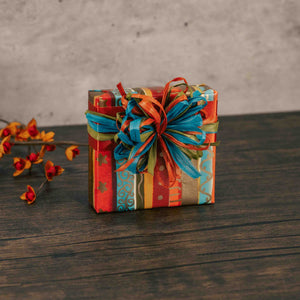 a sampler box of assorted chocolates is wrapped in fall stripe paper and topped with a simple raffia bow