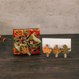 a sampler box of assorted chocolates is wrapped in fall paper and tied with a handmade bow with a mini wooden leaf clothes pin