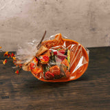 an orange pumpkin plate is packaged with a sampler box of assorted chocolates and a leaf pouch