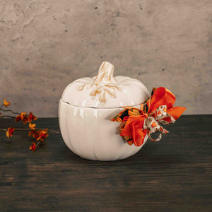 a white pumpkin candy bowl with lid is filled with fall sweet treats