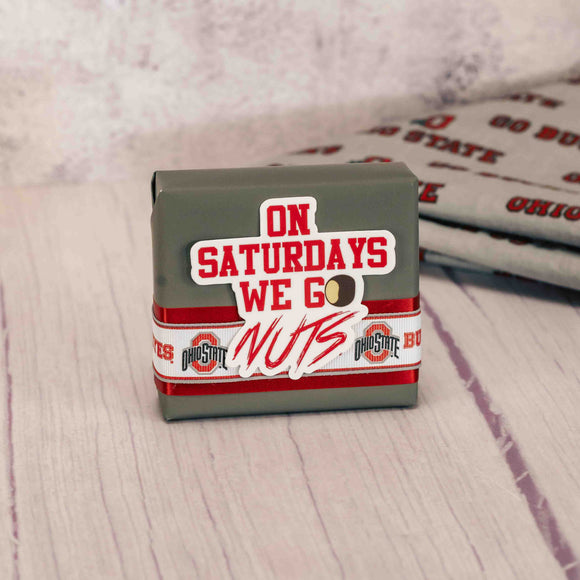 a sampler box of assorted chocolates wrapped in gray and topped with a sticker that reads 'on saturdays we go nuts'