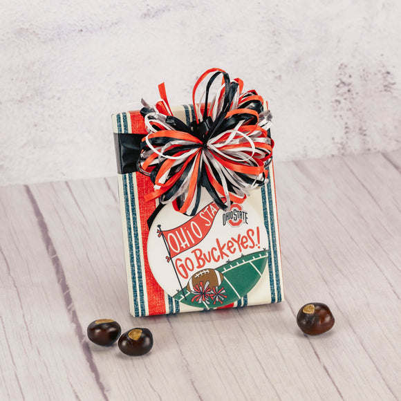 a half pound box of our assorted chocolates is wrapped and topped with a round stone ornament that reads 'go buckeyes'