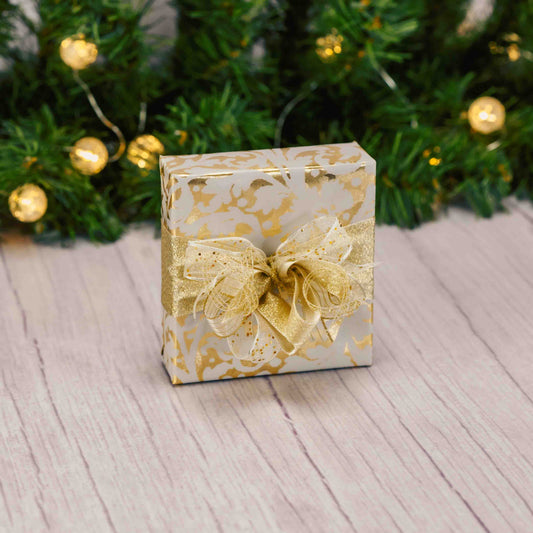 A sampler box of assorted chocolates is wrapped in gold paper and topped with a handmade bow.