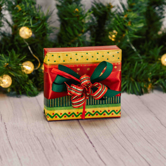 a sampler box of assorted chocolates wrapped in gold, green and red striped paper with a festive handmade bow on top