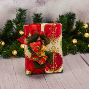 a half pound box of assorted chocolates is wrapped in red and green ornament paper and topped with a stunning handmade bow. choose mil or milk and dark assortment