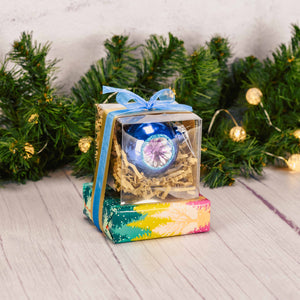 a sampler box of assorted chocolates topped with a vintage glass ornament on top