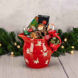 a red ceramic pitcher with winter berries on it is filled with candy and treats