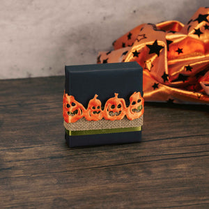 a sampler box of assorted chocolates wrapped in black and tied with jack-o-lantern ribbon