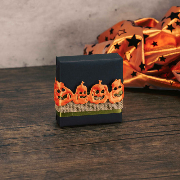 a sampler box of assorted chocolates wrapped in black and tied with jack-o-lantern ribbon