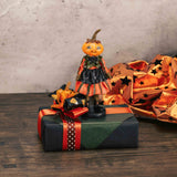 a resin pumpkin girl figurine sits atop a box full of spooky treats!