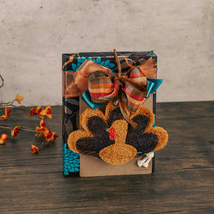 a half pound box of assorted chocolates wrapped festively in fall with a turkey shaped kitchen scrubber made of all natural materials 

