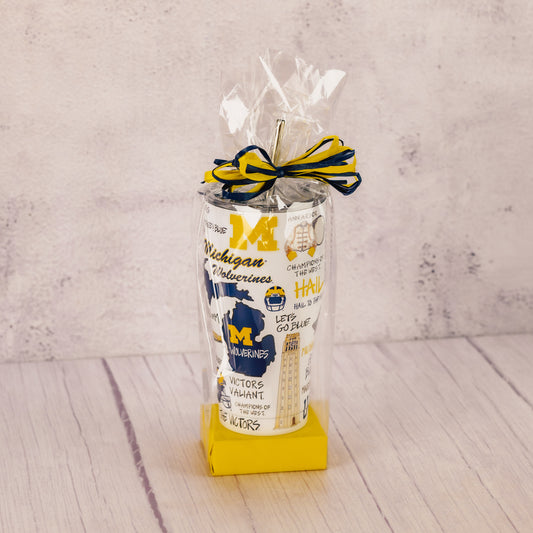 a tall tumbler cup with lid and straw featuring all things Michigan football is packaged with some sweet treats