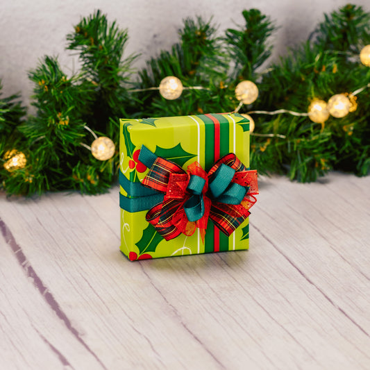 a sampler box of assorted chocolates is wrapped in holly print paper and tied with a lovely handmade bow
