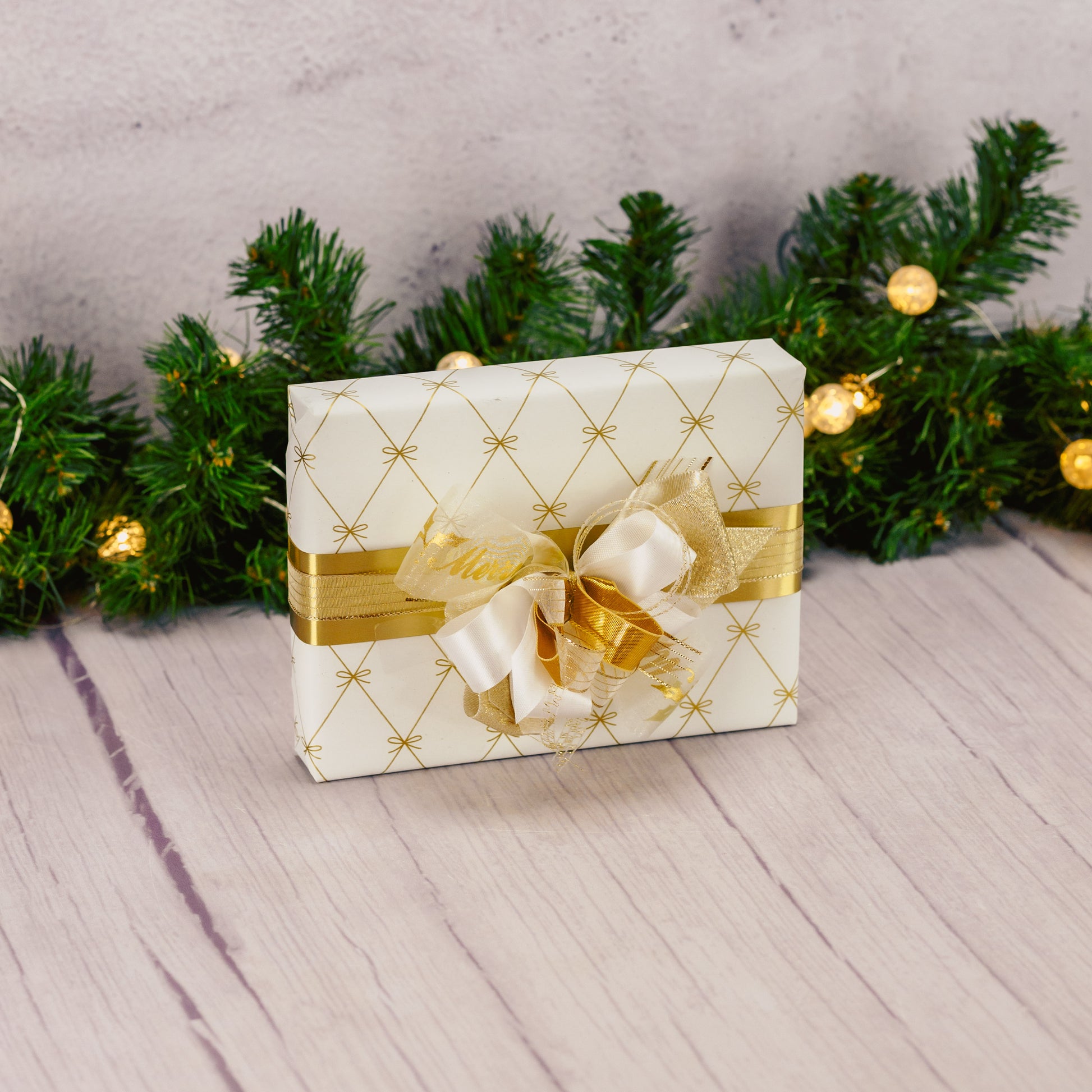 a half pound box of assorted chocolates is wrapped and tied with a lovely handmade bow in ivory and gold colors