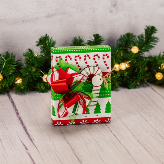 a half pound box of assorted chocolates is wrapped in candy cane paper and topped with a wooden candy cane clip ornament