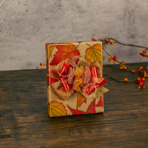 a half pound box of assorted chocolates is wrapped in fall leaf paper and topped with a handmade bow.