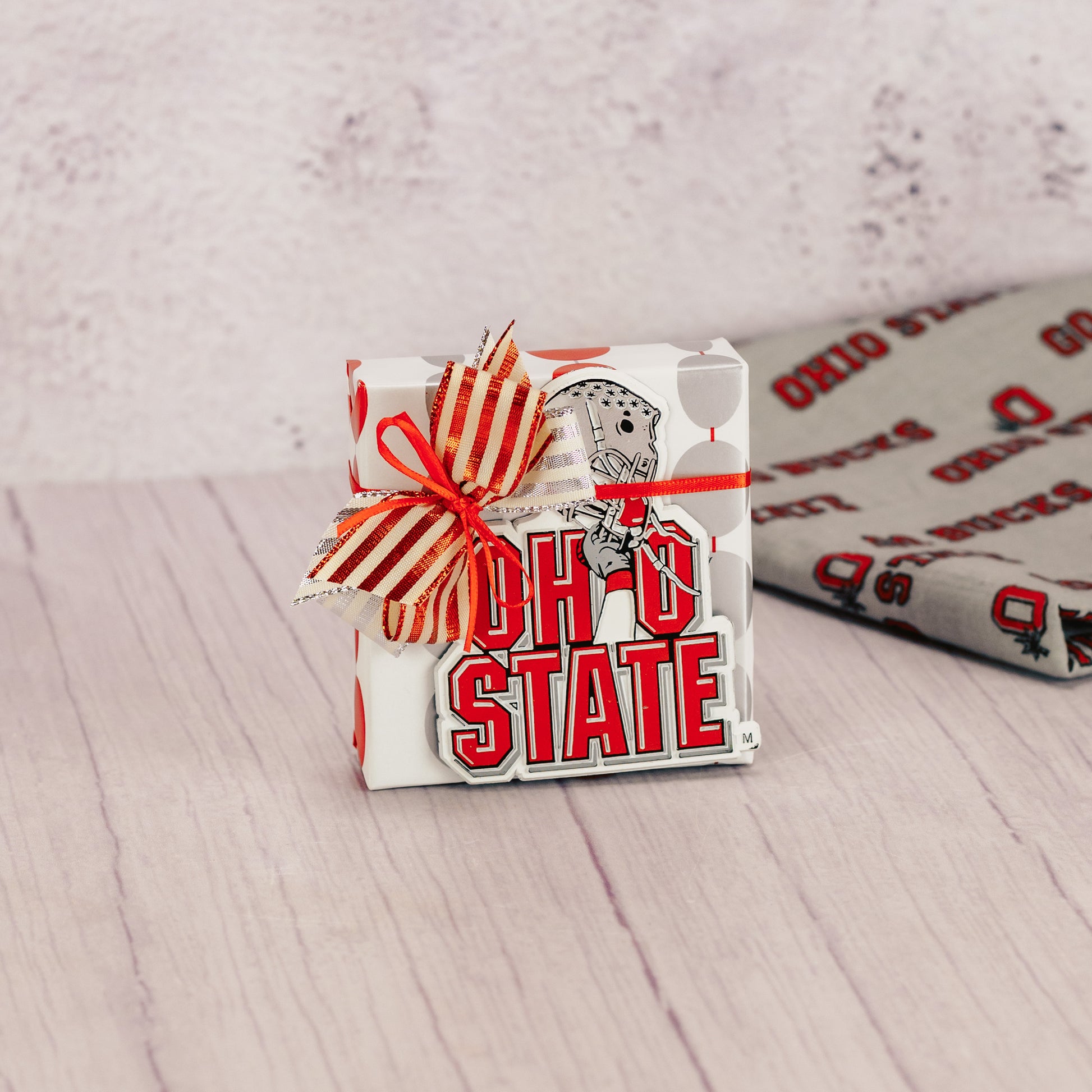 a sampler box of assorted chocolates wrapped and topped with an Ohio State helmet magnet