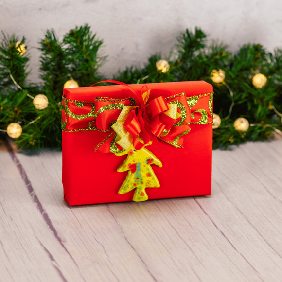 a half pound of assorted chocolates is wrapped in red and topped with a ceramic tree ornament made locally by individuals from RTC services program