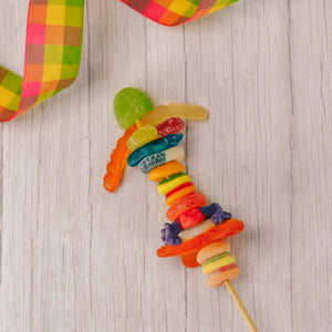 a kebob of assorted gummi pieces like: fruit slices, frogs, worms, cherries and more!