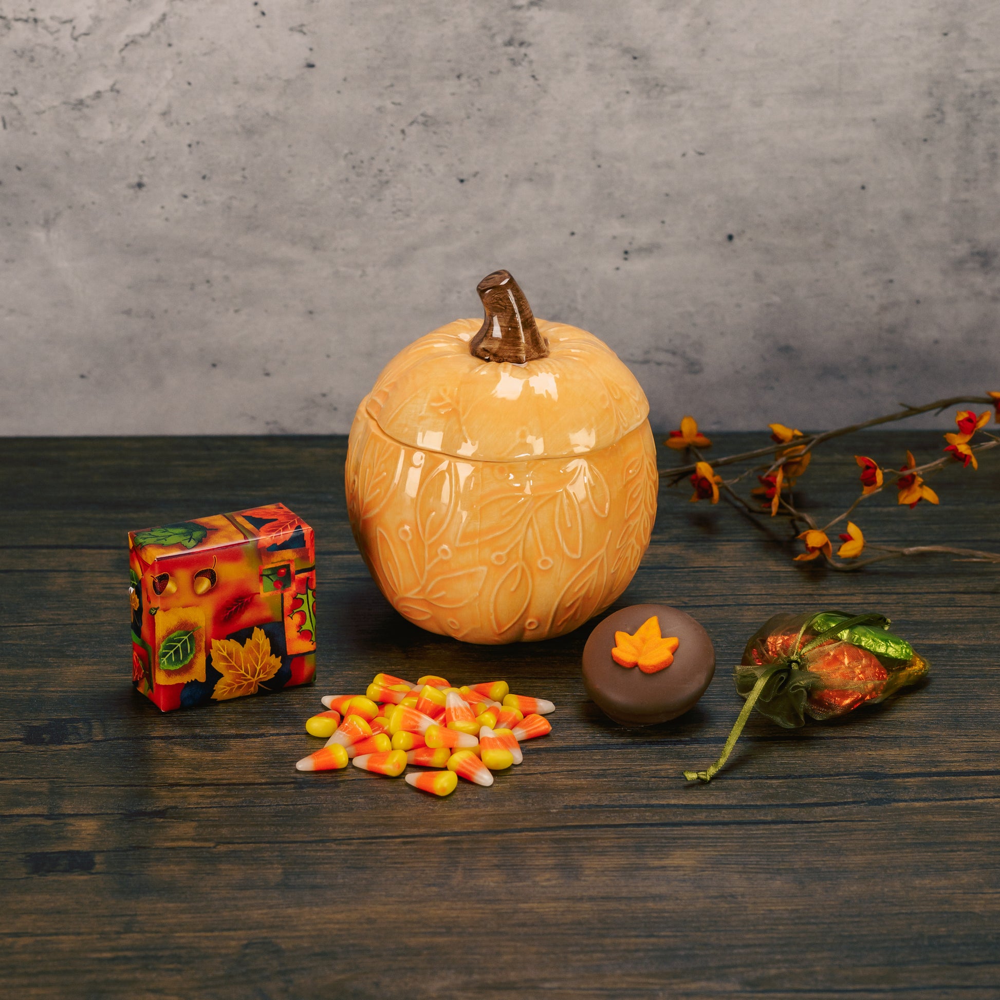 a ceramic pumpkin candy bowl with lid is filled with festive fall treats. assorted pumpkin colors. 