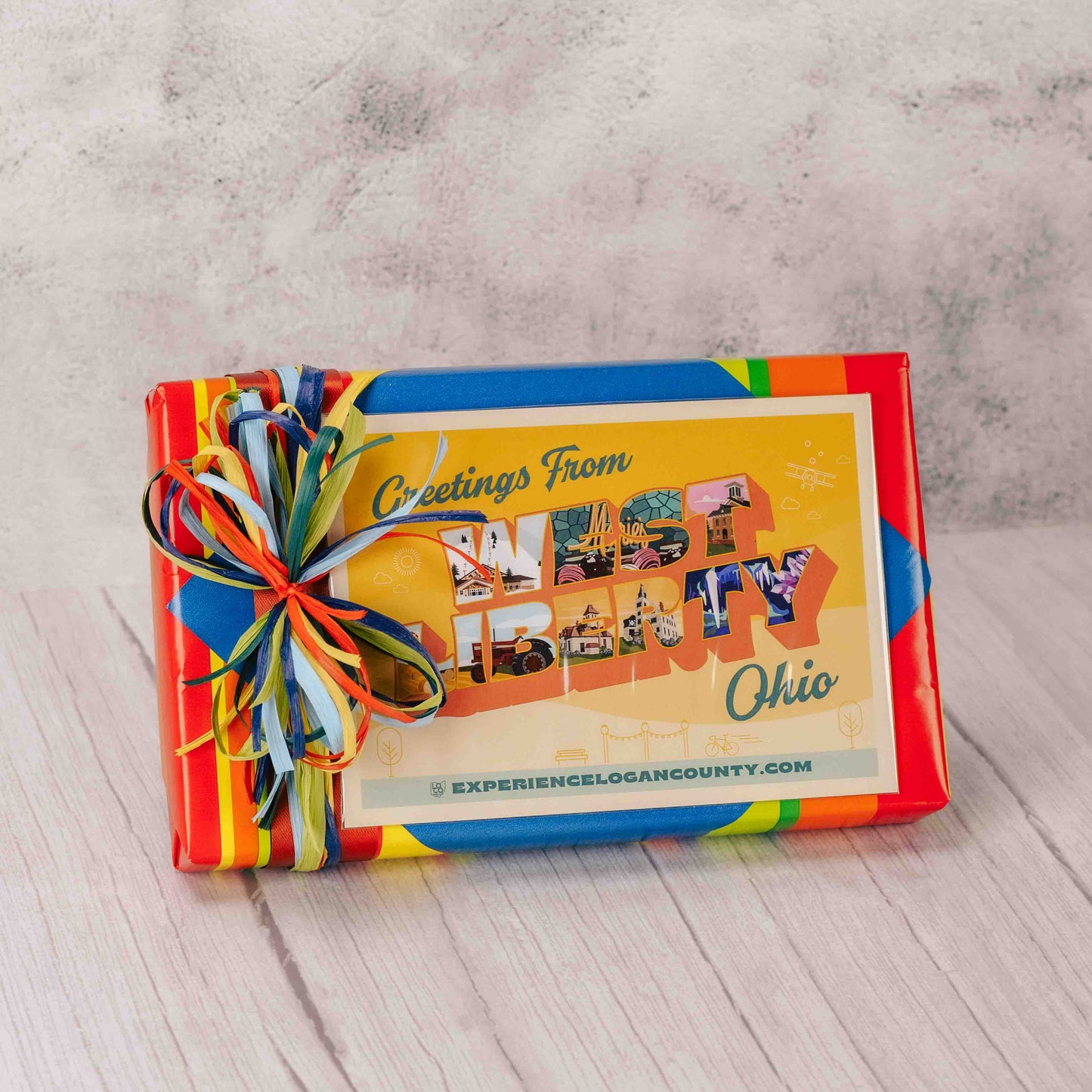 a one pound box of assorted chocolates is topped with a West Liberty, Ohio postcard