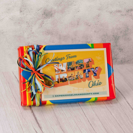 a one pound box of assorted chocolates is topped with a West Liberty, Ohio postcard