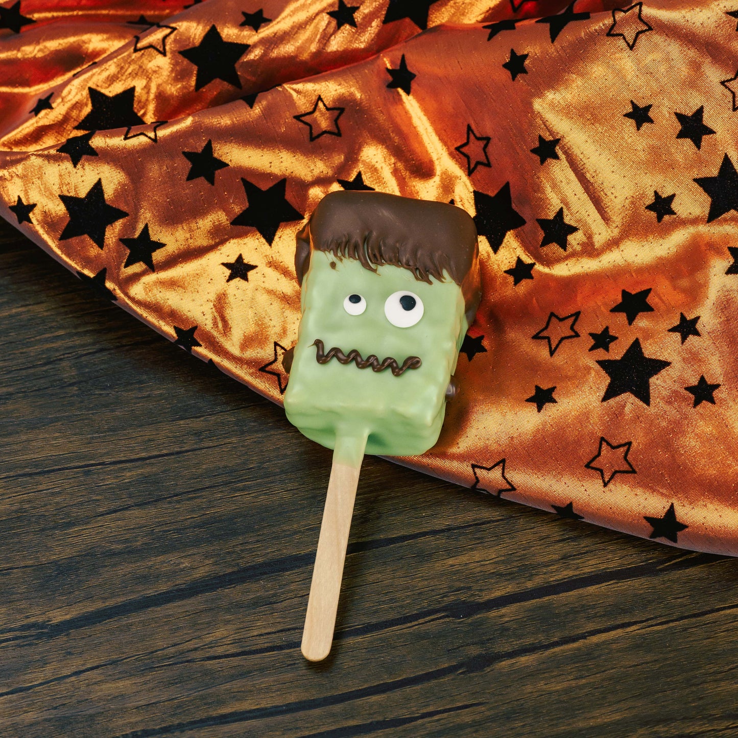 A Rice Krispie Treat on a popsicle stick, covered in green coating, with sugar eyes and milk chocolate for hair and a mouth, What a fun spook-tacular Halloween treat! Individually packaged.