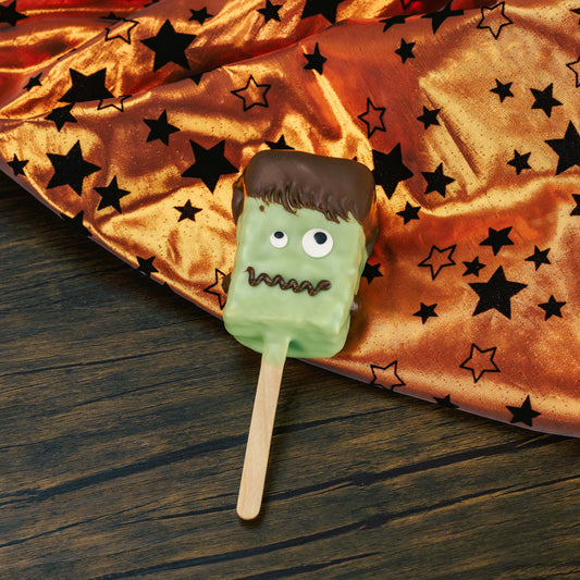 A Rice Krispie Treat on a popsicle stick, covered in green coating, with sugar eyes and milk chocolate for hair and a mouth, What a fun spook-tacular Halloween treat! Individually packaged.