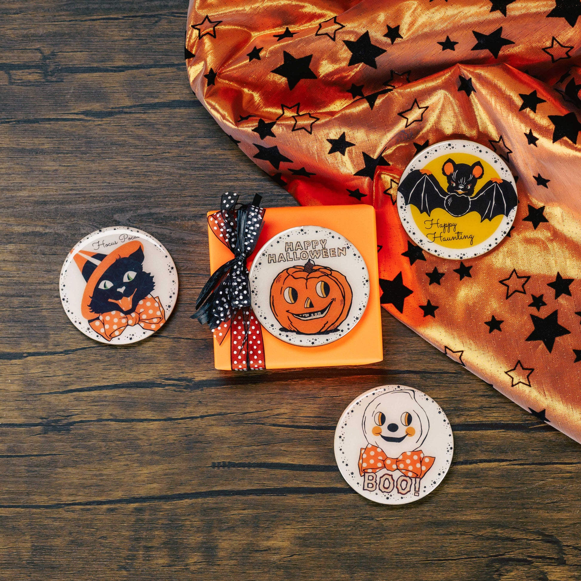 a round wooden Halloween magnet (choose a cat, bat, ghost or jack-o-lantern) is placed on a sampler box of assorted chocolates.