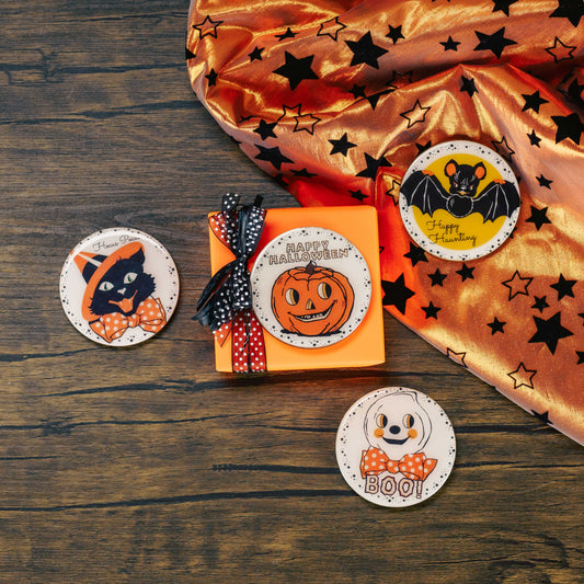 a round wooden Halloween magnet (choose a cat, bat, ghost or jack-o-lantern) is placed on a sampler box of assorted chocolates.