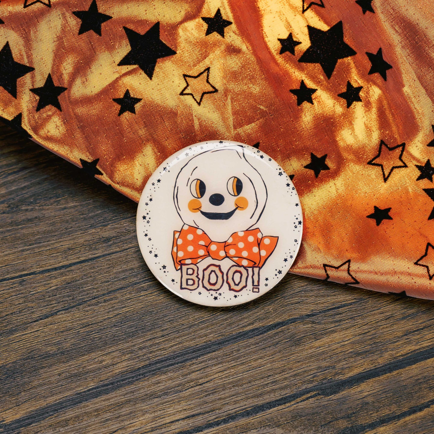 a round wooden ghost Halloween magnet, that reads 'boo' is placed on a sampler box of assorted chocolates