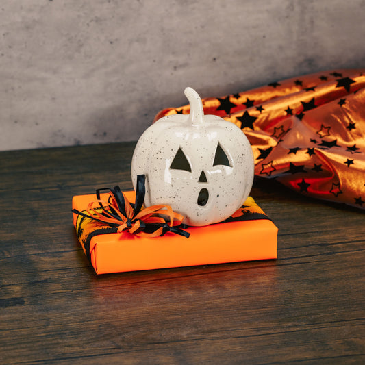 a light up stoneware jack-o-lantern sits on top of a half pound box of assorted chocolates. 