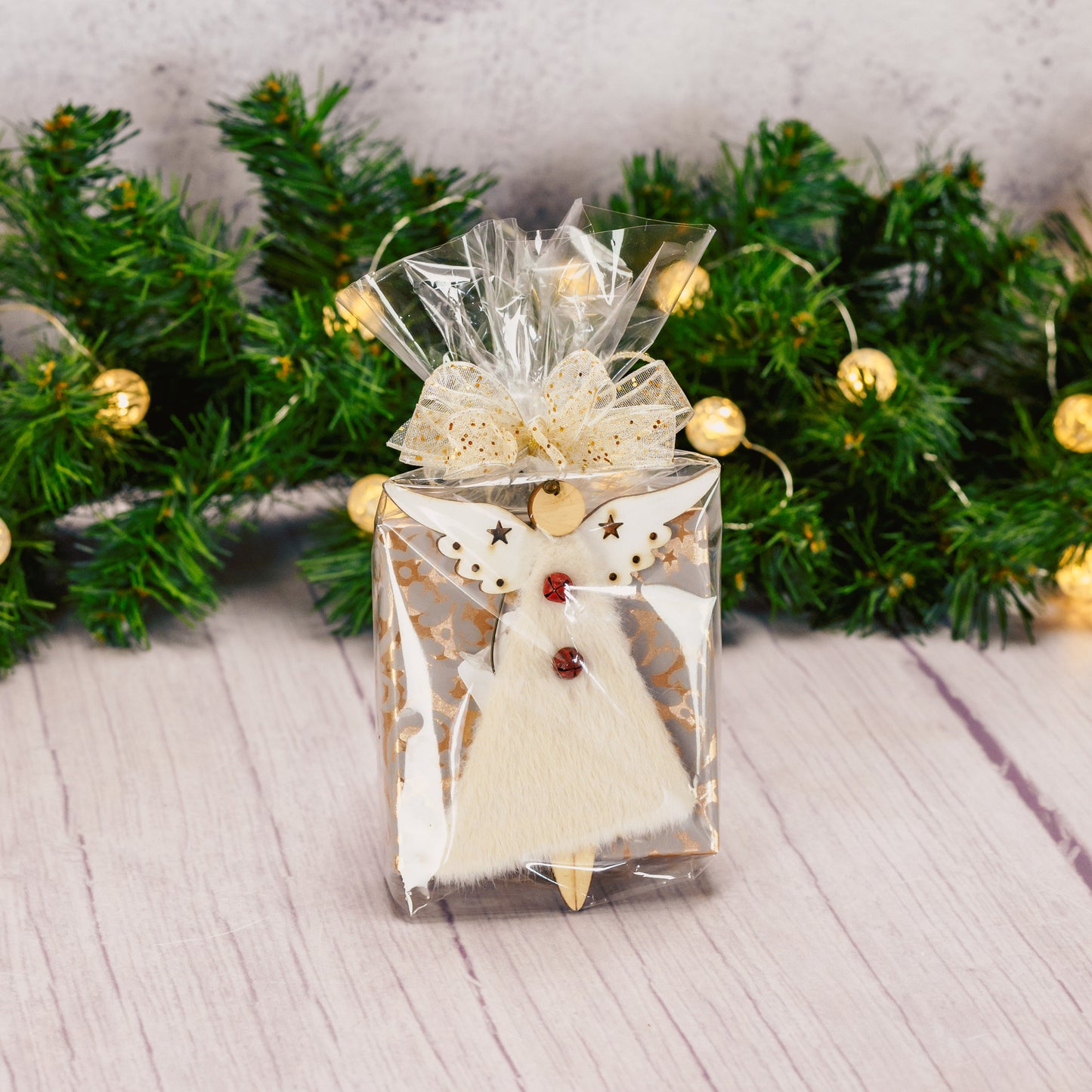 a fuzzy wooden angel ornament is packaged with a sampler box of assorted chocolates. assorted angel designs