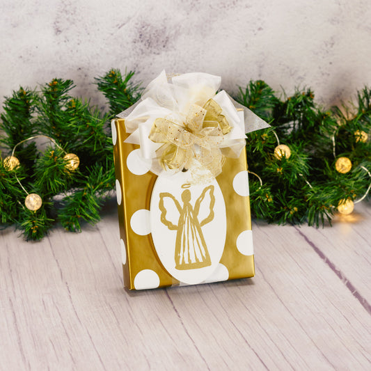 a half pound box of assorted chocolates is wrapped in ivory and gold and topped with a wooden oval angel ornament