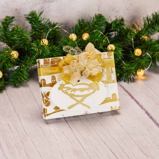 a half pound box of assorted chocolates is wrapped in white and gold and topped with a wooden oval nativity ornament