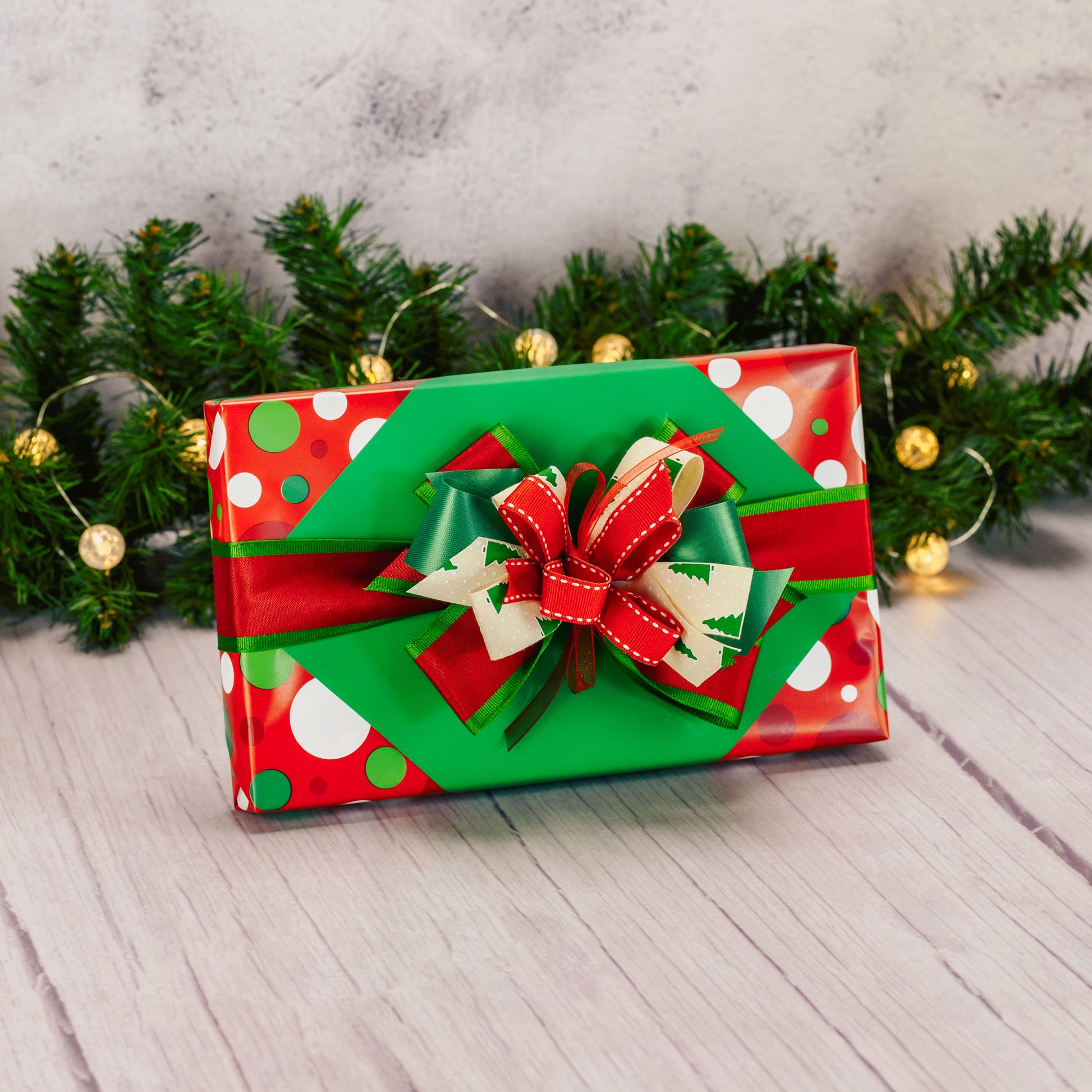 a one pound box of assorted chocolates is wrapped and bowed in green and red colors.