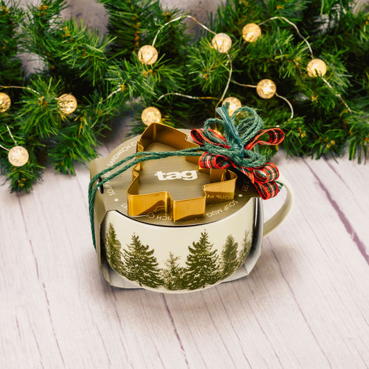 a soup mug with pine trees all around is filled with sweet treats and comes with a tree stencil, for cookies, sandwiches or coffee art. 