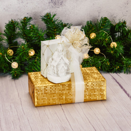 a white resin LED church figurine is packaged with sweet treats and displayed in a gift stack of white and gold