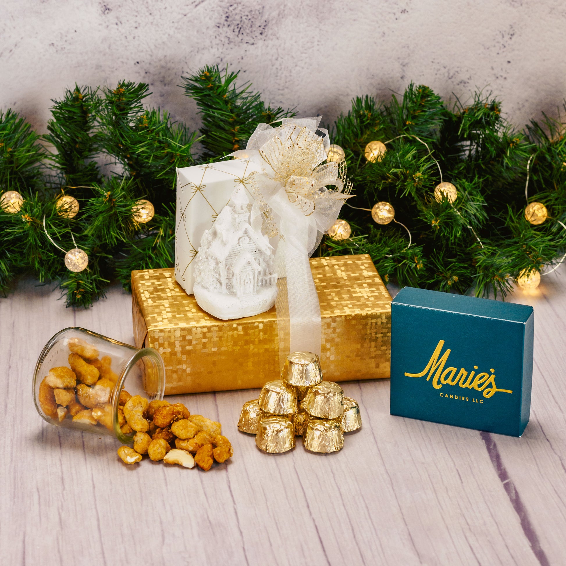 a white resin LED church figurine is packaged with sweet treats and displayed in a gift stack of white and gold