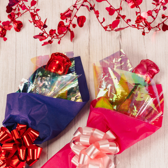 long stem milk chocolate rose wrapped in red or pink foil placed in tissue paper and tied with a bow. 