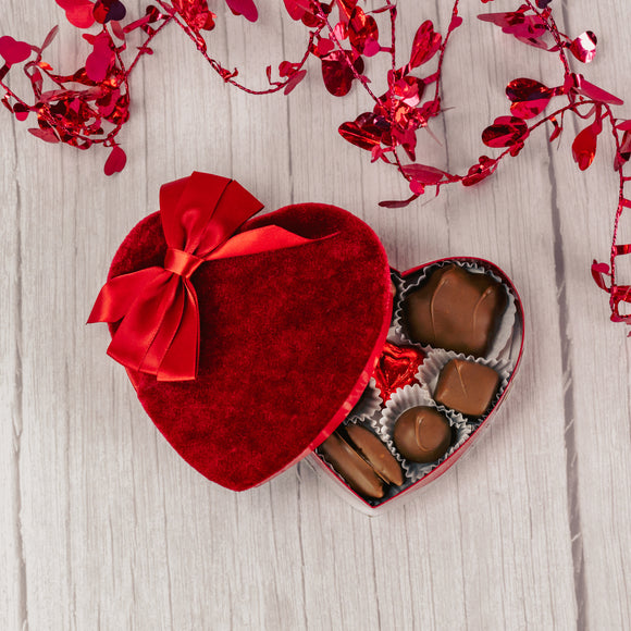 a quarter pound assorted chocolates inside a red velvet heart shaped box.