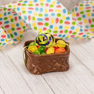 a milk chocolate basket is filled with fruit jelly beans and wrapped in saran and tied with curling ribbon.