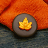Oreo cookie dipped in milk chocolate with fall leaf decoration on top.