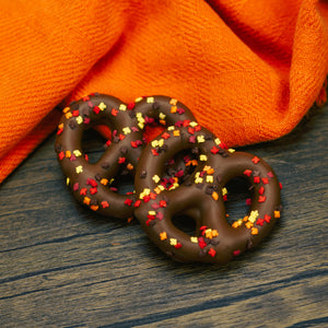 Jumbo pretzel coated in milk chocolate with fall leaf sprinkles.
