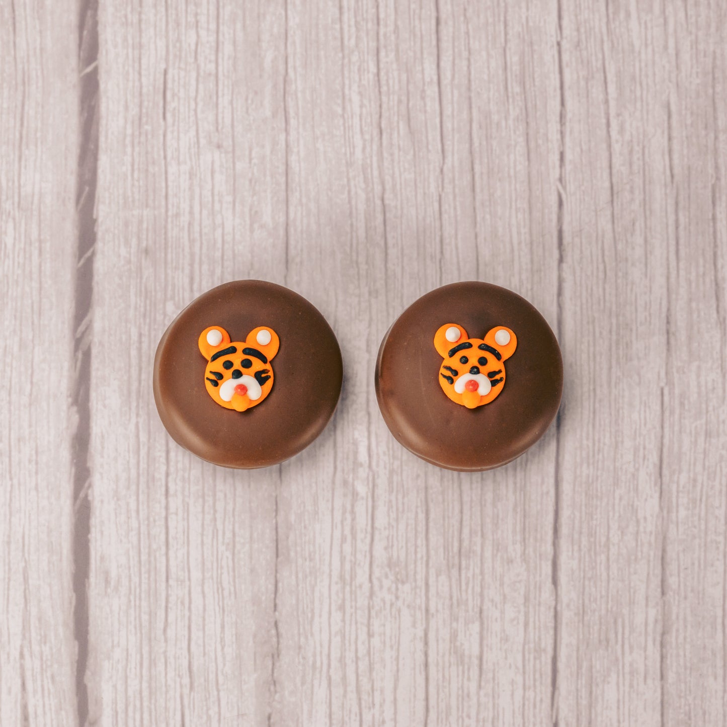 an oreo cookie covered in milk chocolate with a tiger face sugar decoration on top.