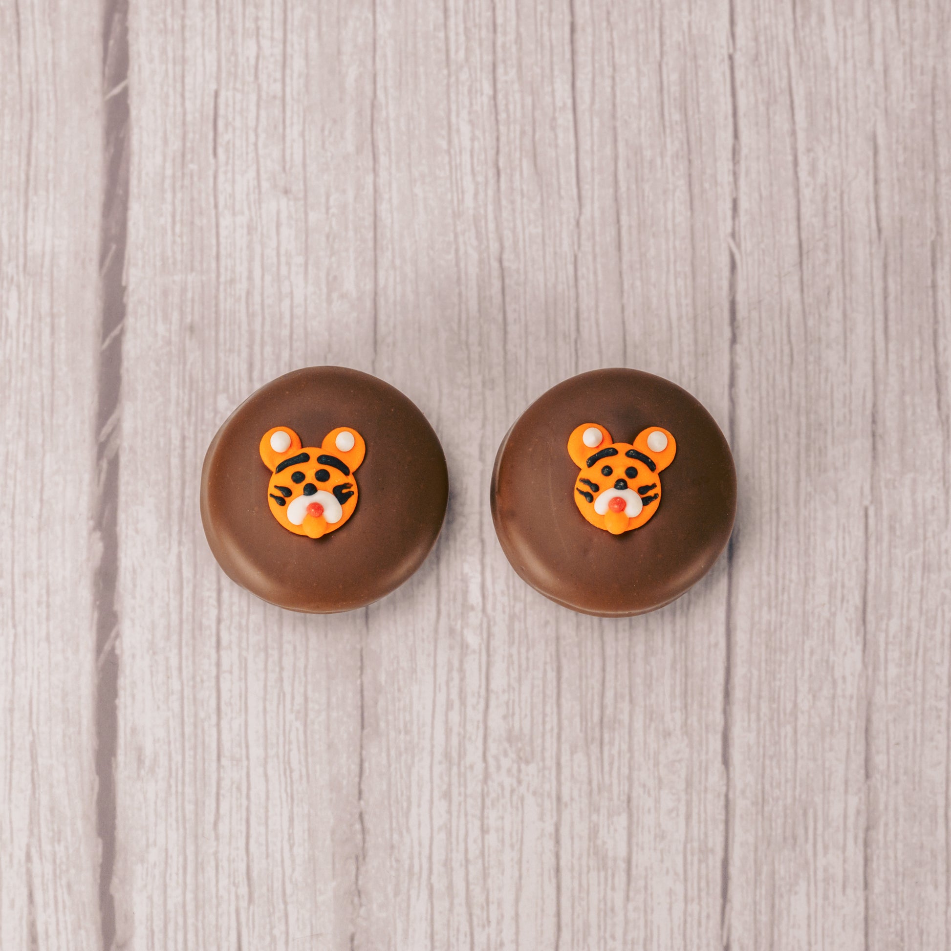 an oreo cookie covered in milk chocolate with a tiger face sugar decoration on top.