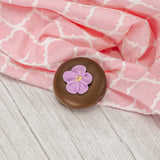 A crunchy Oreo cookie dipped in smooth milk chocolate with a sugar flower decoration on top.