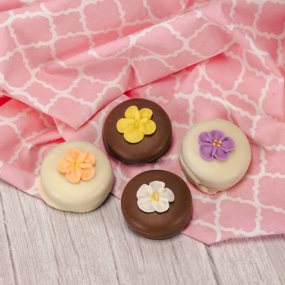 A crunchy Oreo cookie dipped in smooth milk chocolate or rich white coating with a sugar flower decoration on top.