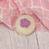 A crunchy Oreo cookie dipped in rich white coating with a sugar flower decoration on top.